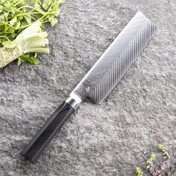 Shun nakiri knife with fresh herbs on a stone surface
